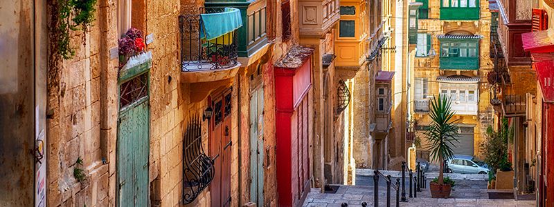 Smala gator med färgglada hus och balkonger i Valletta, Malta.